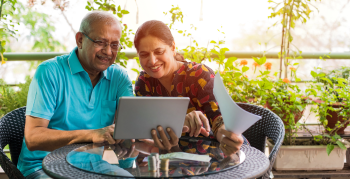 older couple sitting outside with a computer