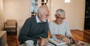 A happy senior couple calculating their finances in a beautiful home.