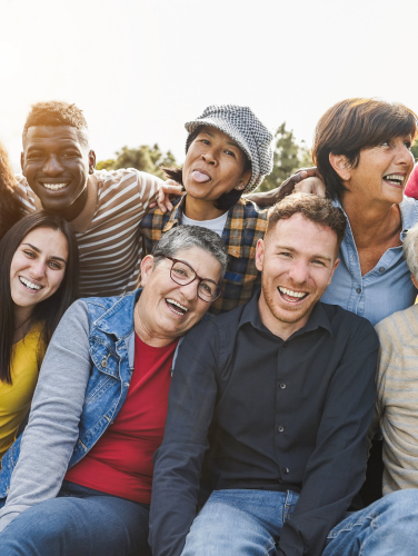 Group of multigenerational people smiling in front of camera - Multiracial friends od different ages having fun together - Main focus on caucasian senior faces