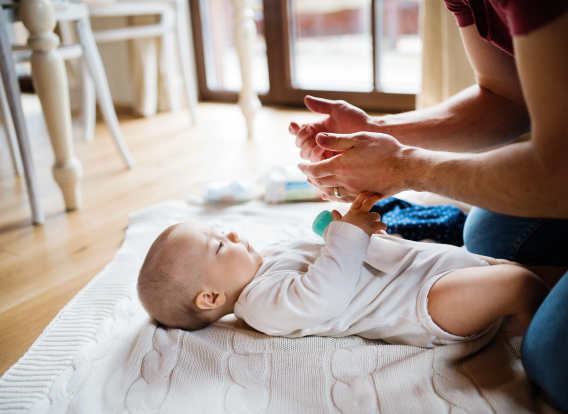 Photo of father playing with baby on blanket