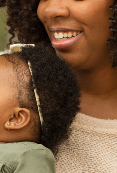 A father and mother holding a baby while smiling.